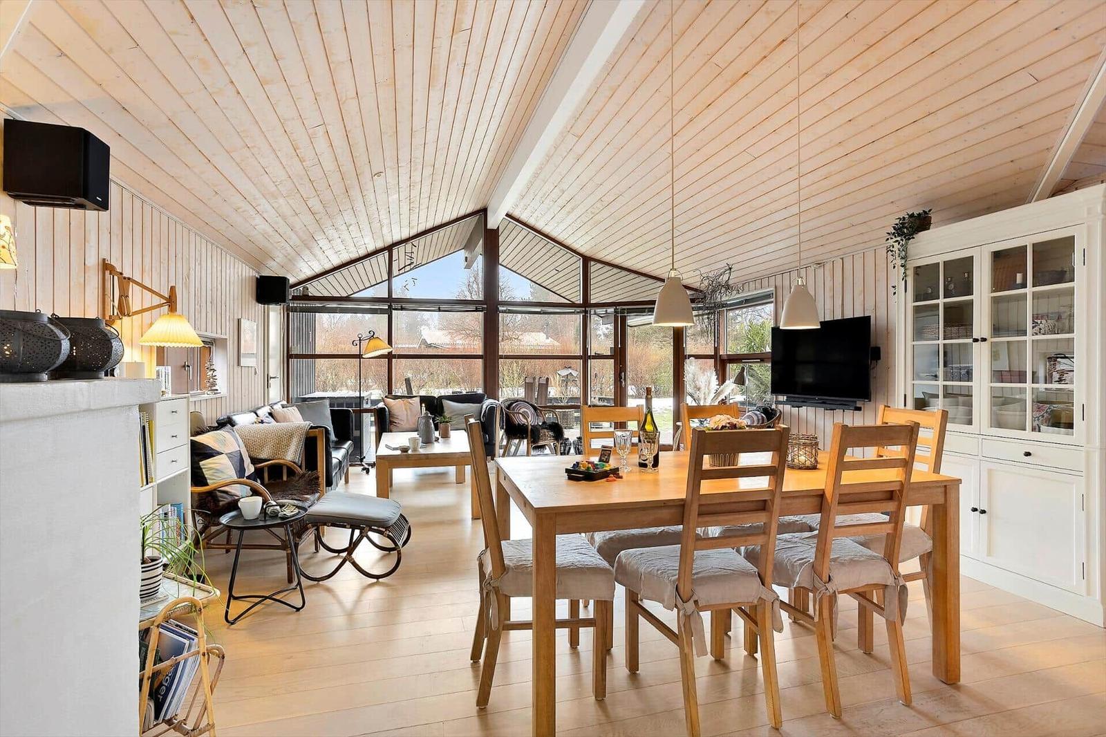 Living and dining area with wooden ceiling, dining table, and TV
