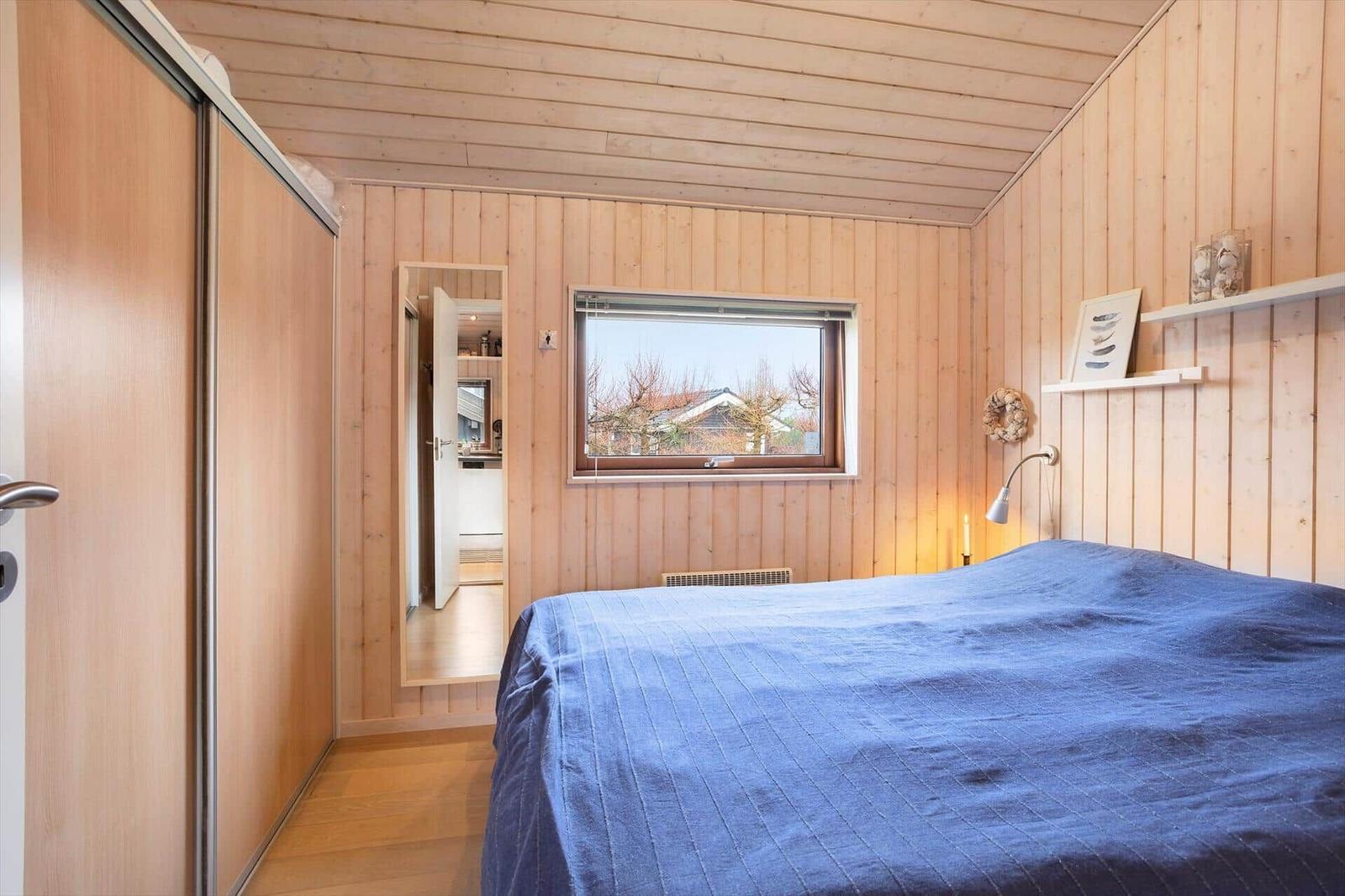 Bedroom with wooden walls, bed, and window for outdoor view.
