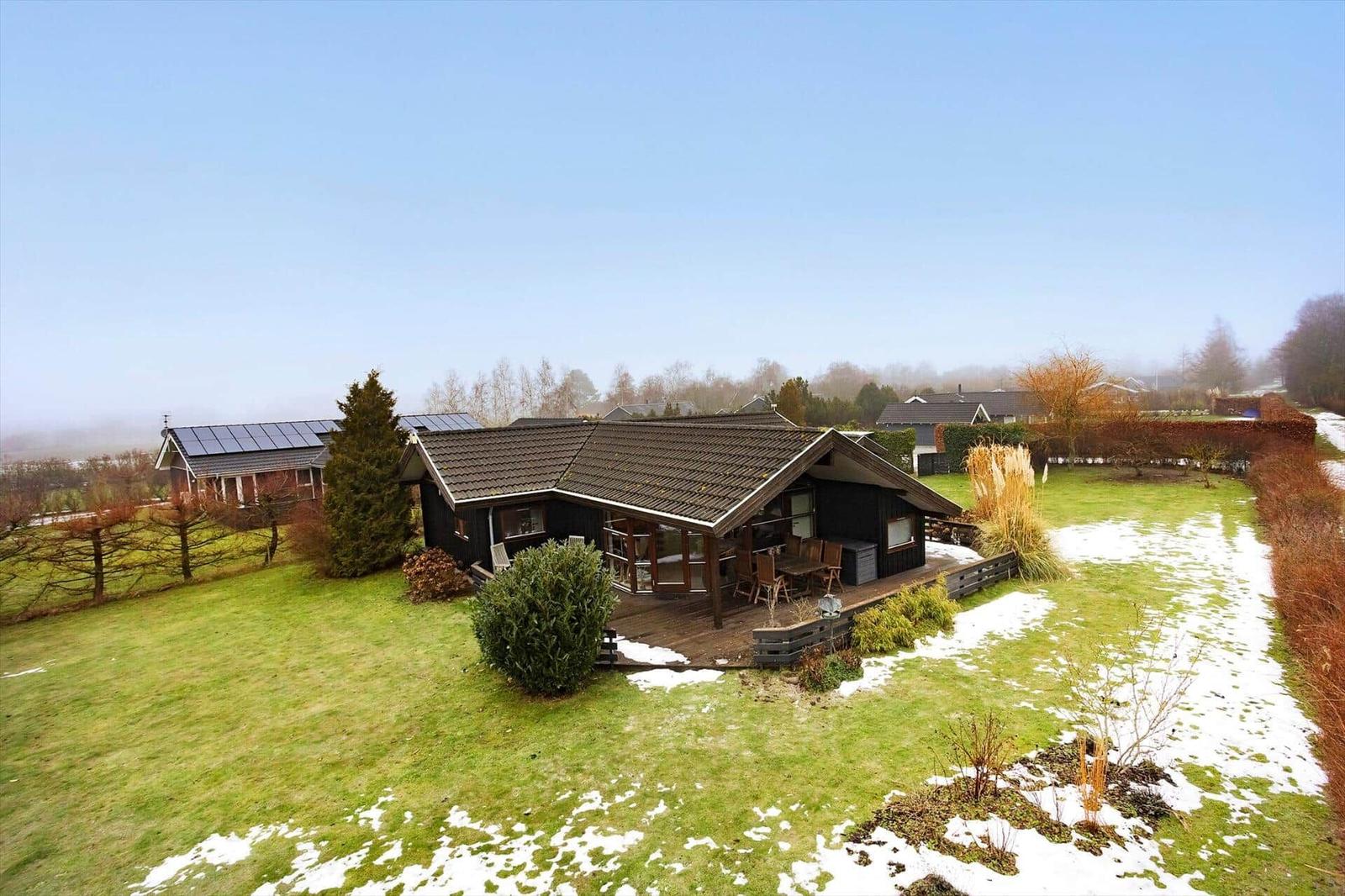 Wooden house with terrace and garden, partially covered in snow.