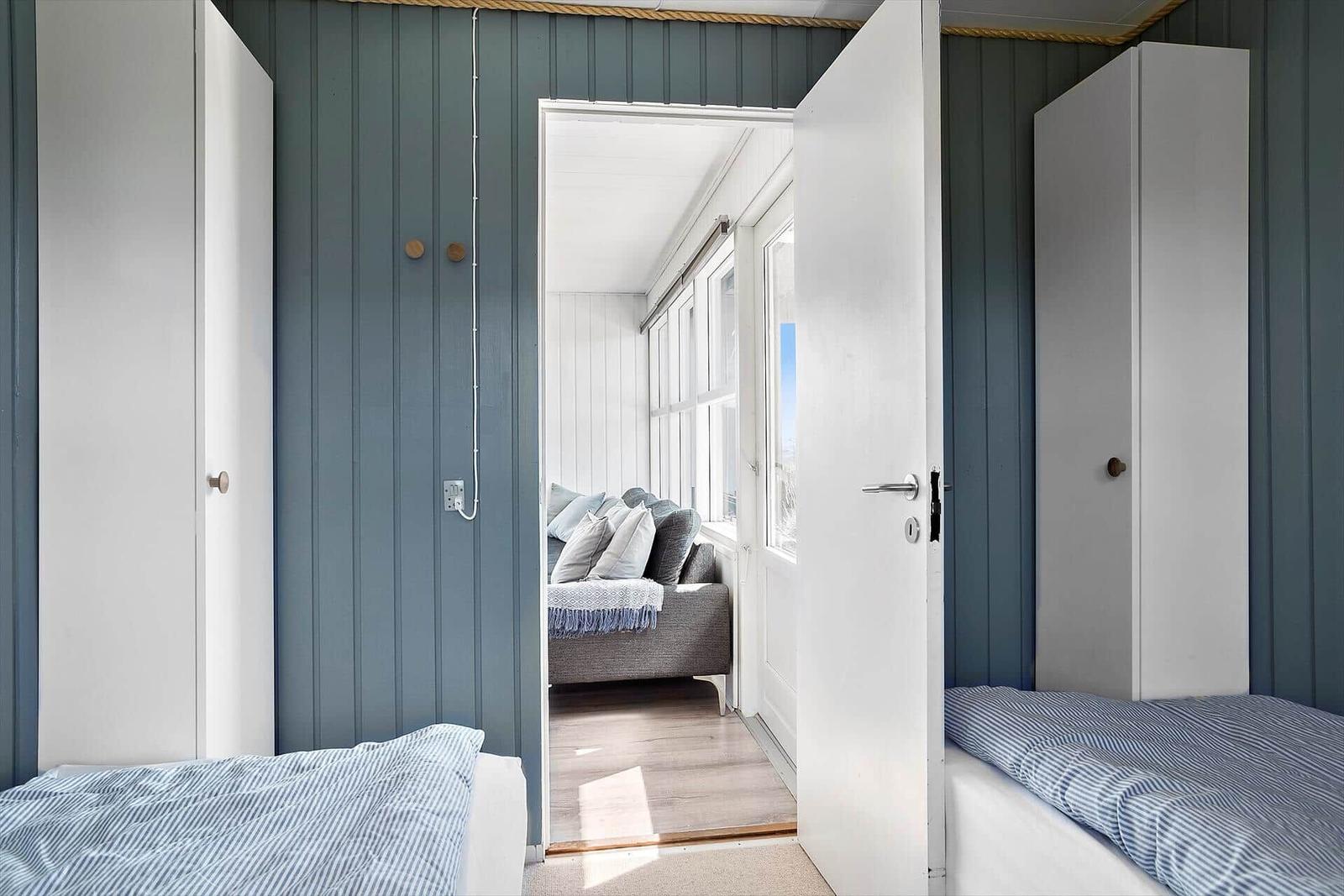 Two bedrooms with view into living area with sofa and windows.