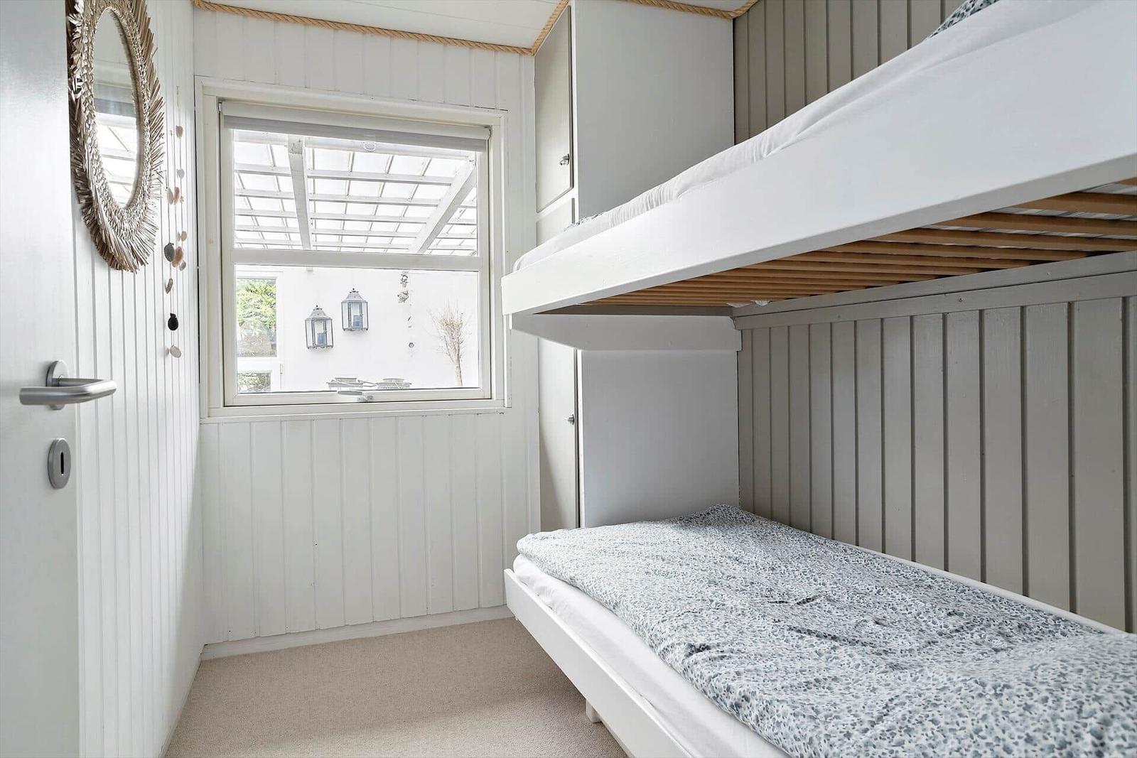 Room with bunk bed, window, and mirror on the wall.