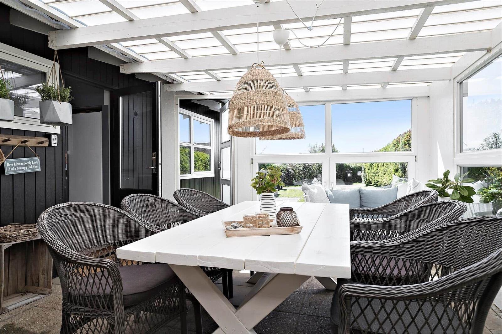 Terrace with white table, dark chairs, and hanging wicker lamps.