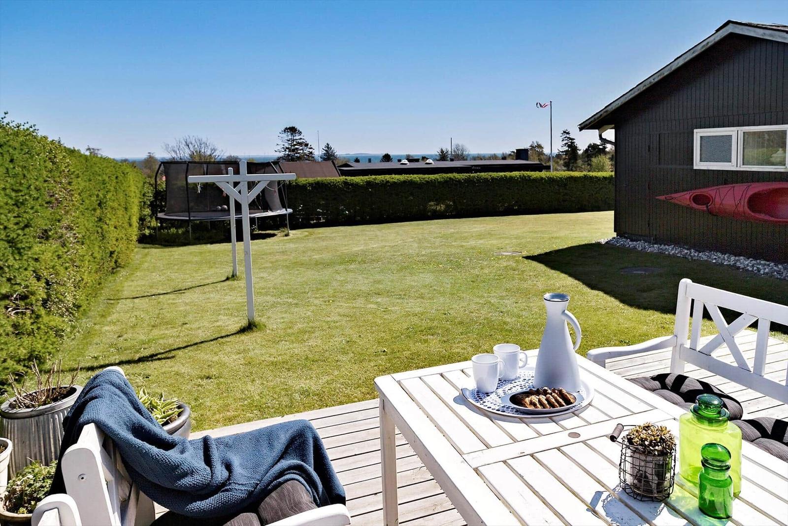 Deck with table, chairs, and view of garden and lake.