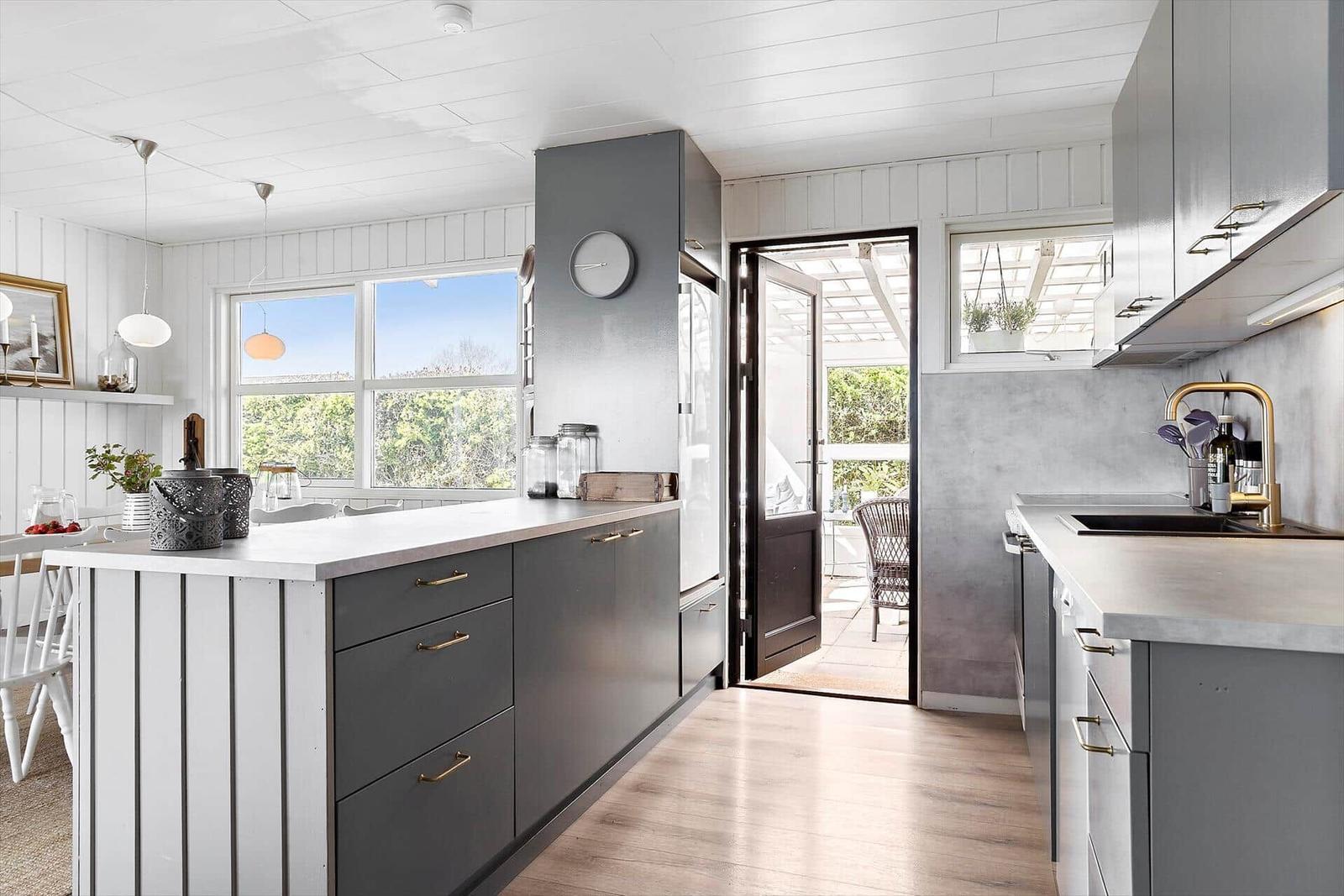Kitchen with gray cabinets, wooden floor, and view of balcony.
