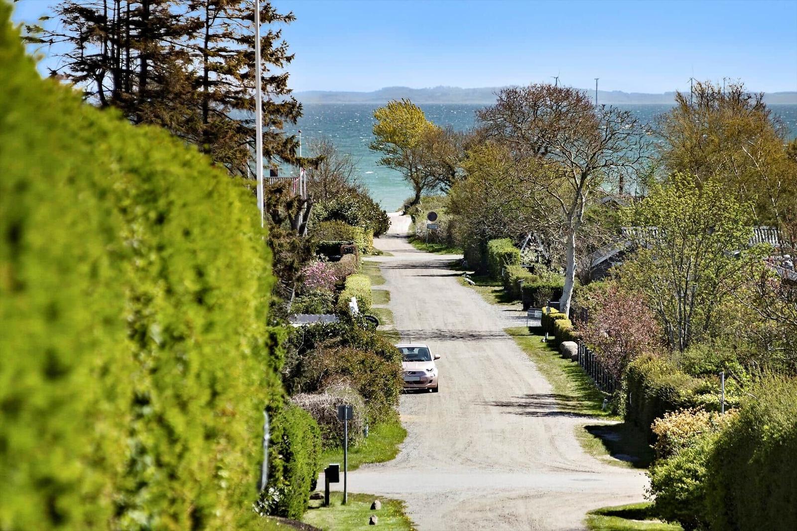 Drive to vacation rental with sea view and green trees.