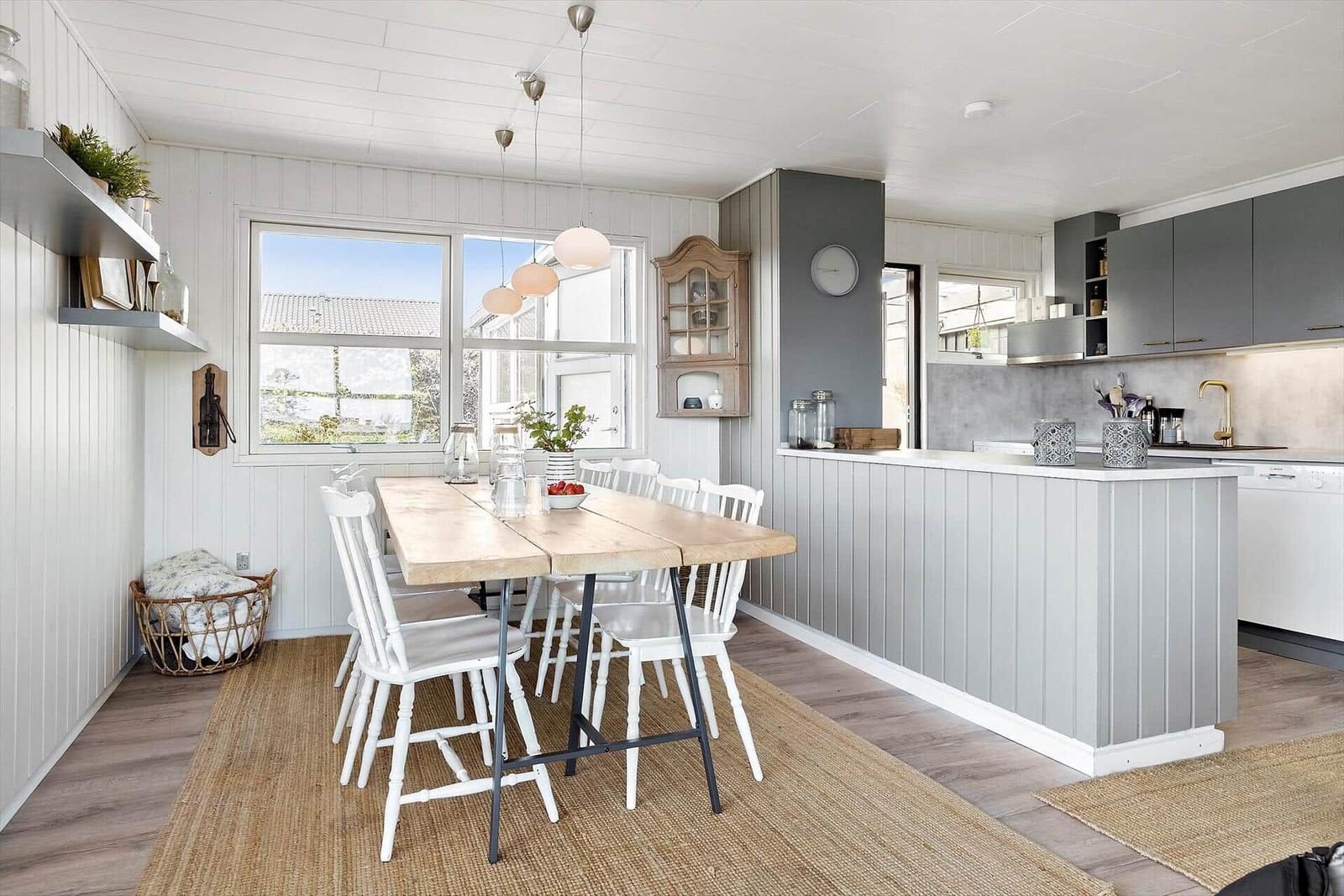 Kitchen with dining area, wooden table, white chairs, and gray cabinets.