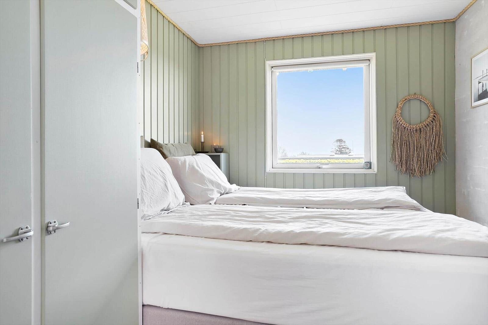 Bedroom with bed, window, and wall decoration.