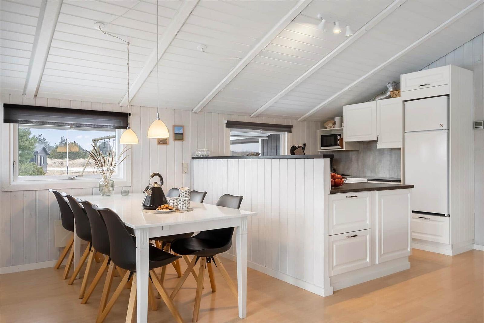 Küche und Essbereich mit weißer Einrichtung und Holzboden.
