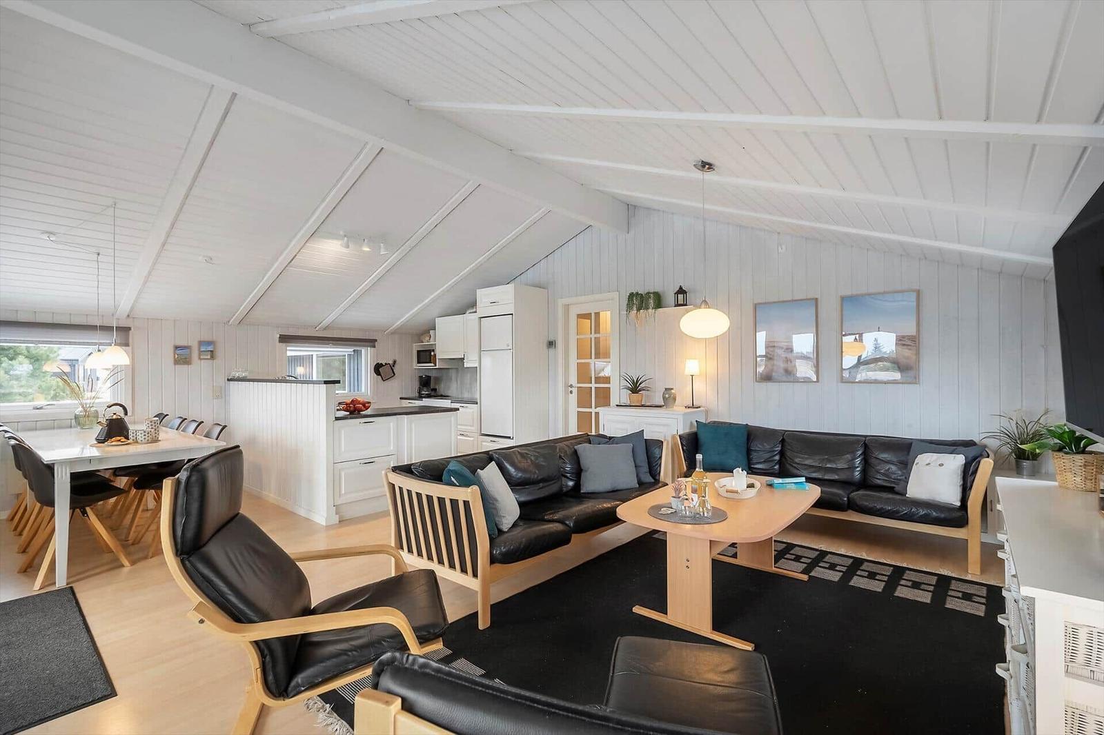 Wohnbereich mit Essbereich, Küche und schwarzen Ledermöbeln.