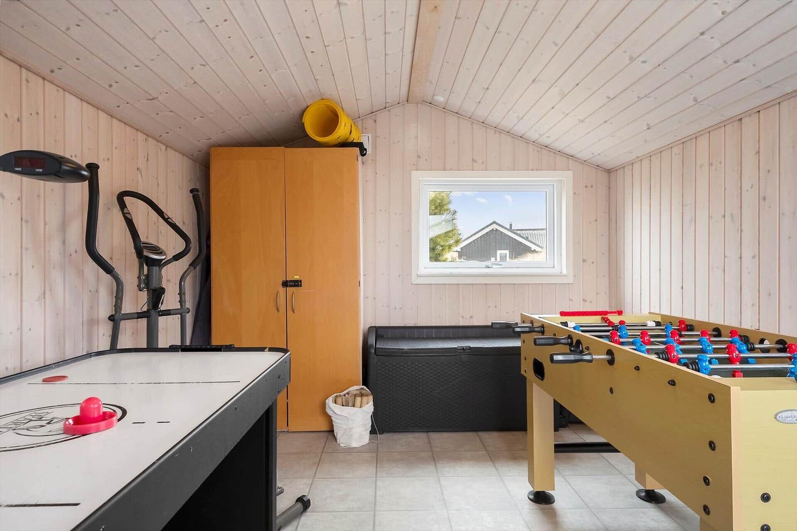 Raum mit Tischfußball, Eisstockschießen und Fitnessgerät.