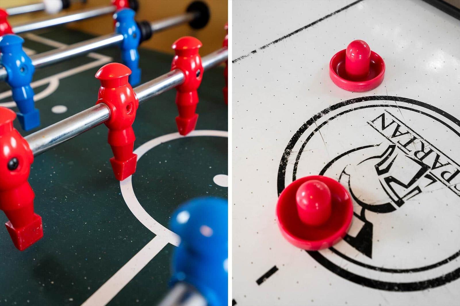Fußballtisch und Air Hockey Tisch mit roten und blauen Spielsteinen.