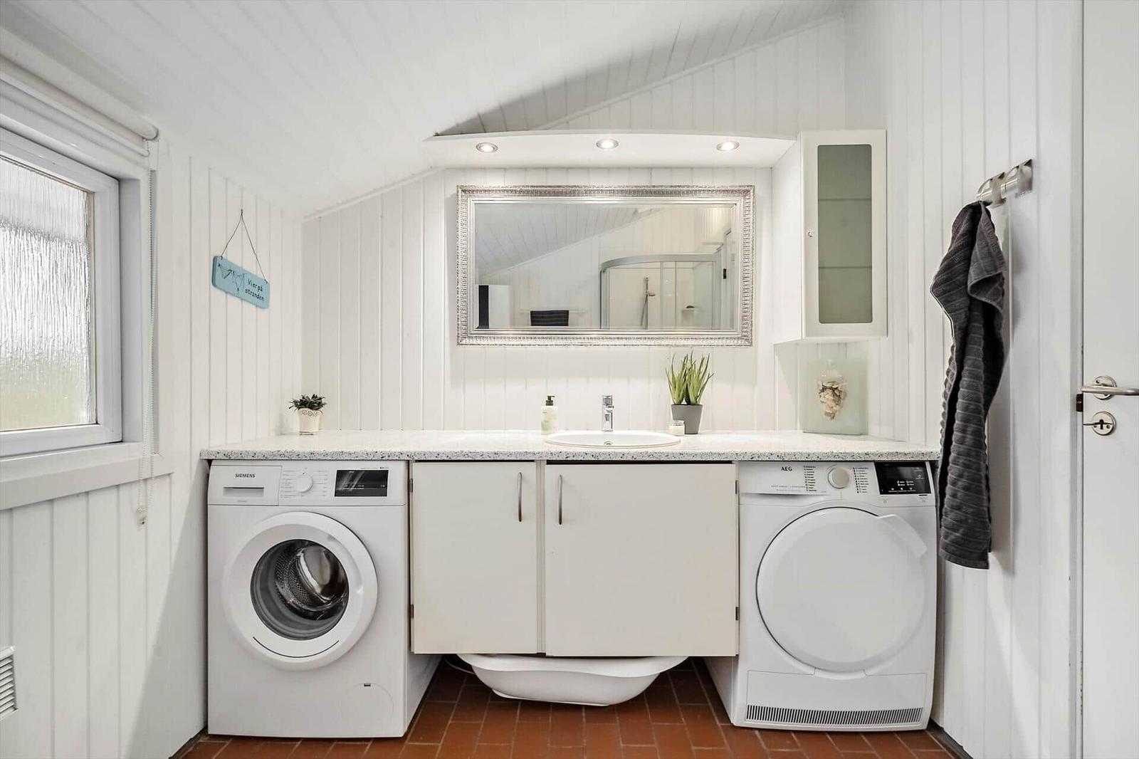 Waschraum mit Waschmaschine, Trockner und Spiegel