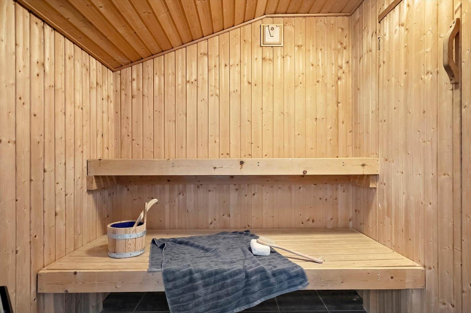 Sauna mit Holzwand, Sitzbank und Holzwaschbecken.