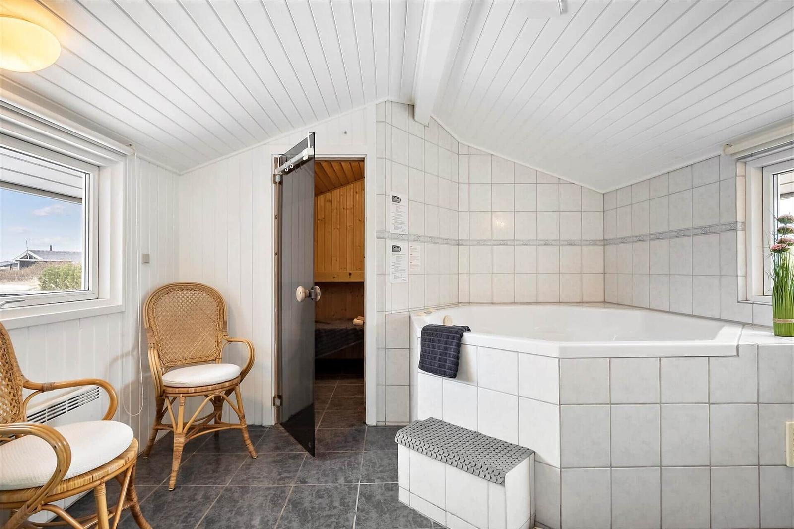 Bad mit Whirlpool, Sauna und zwei Stühlen. Fenster mit Aussicht.