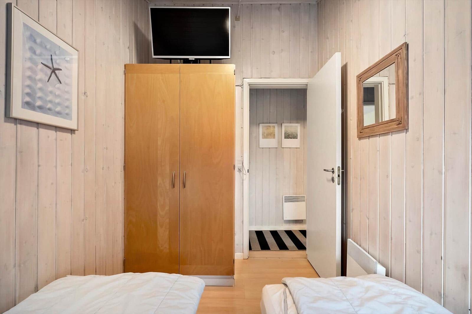 Zwei Betten, Kleiderschrank, TV und Spiegel an den Wänden.