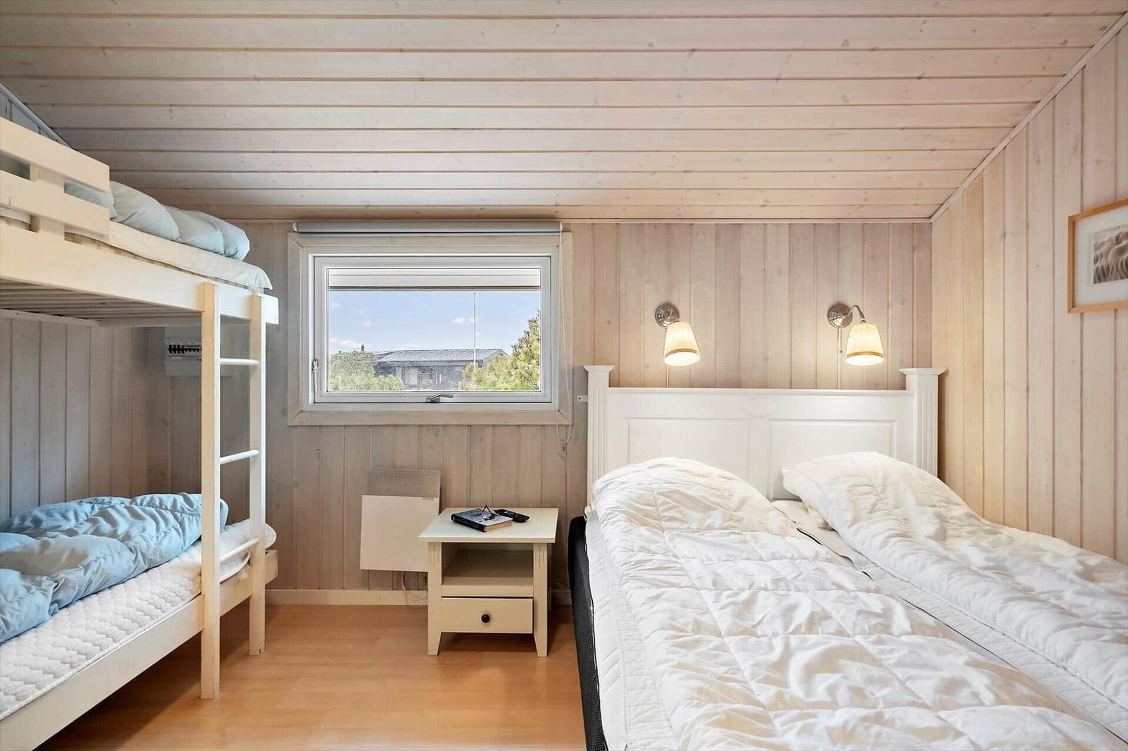 Zimmer mit Doppelbett und Kletterbett, Fenster und Nachttisch.