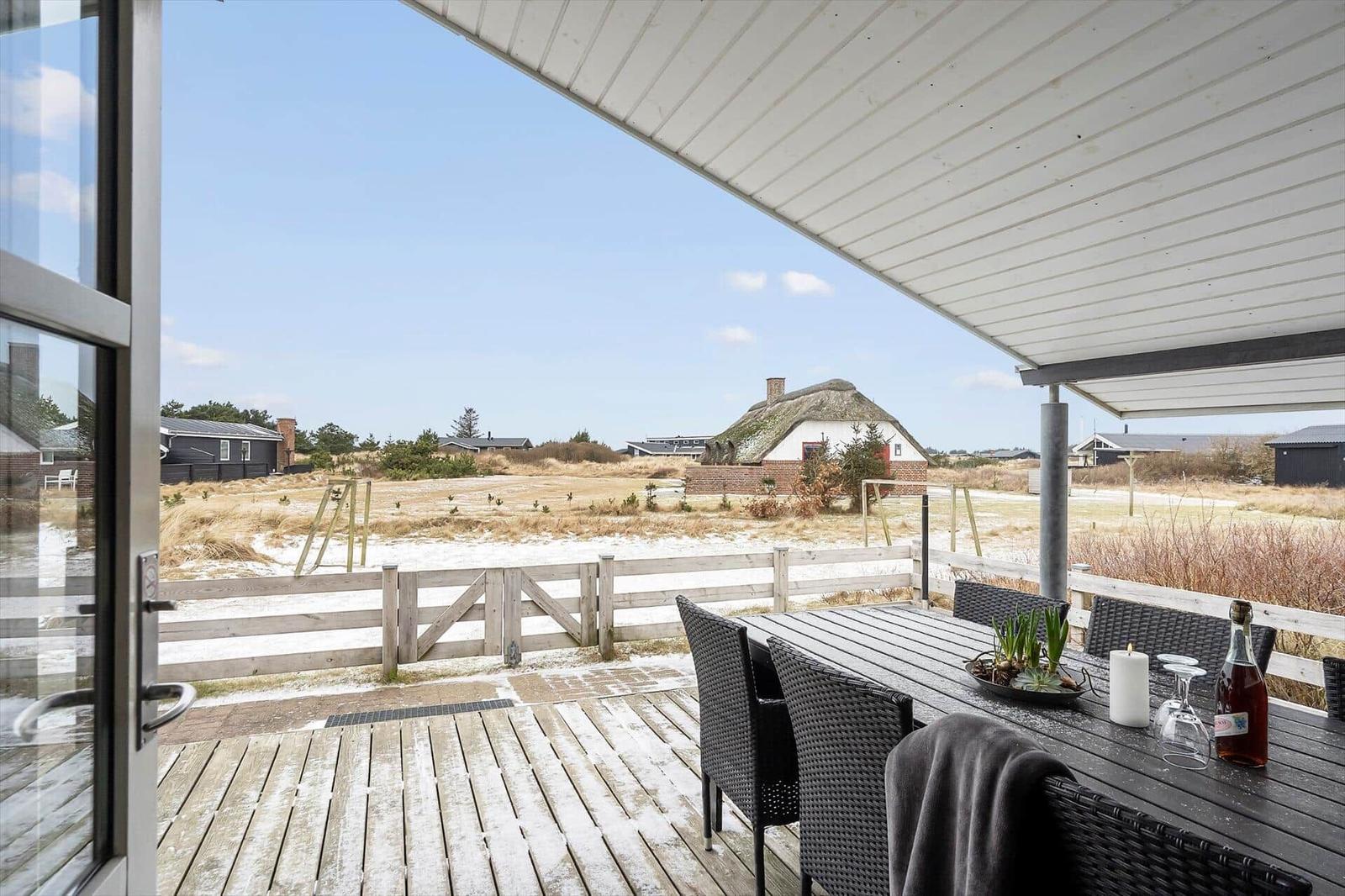 Terrasse mit Tisch und Stühlen, Blick auf eine Landschaft mit einem Dachstuhlhaus.