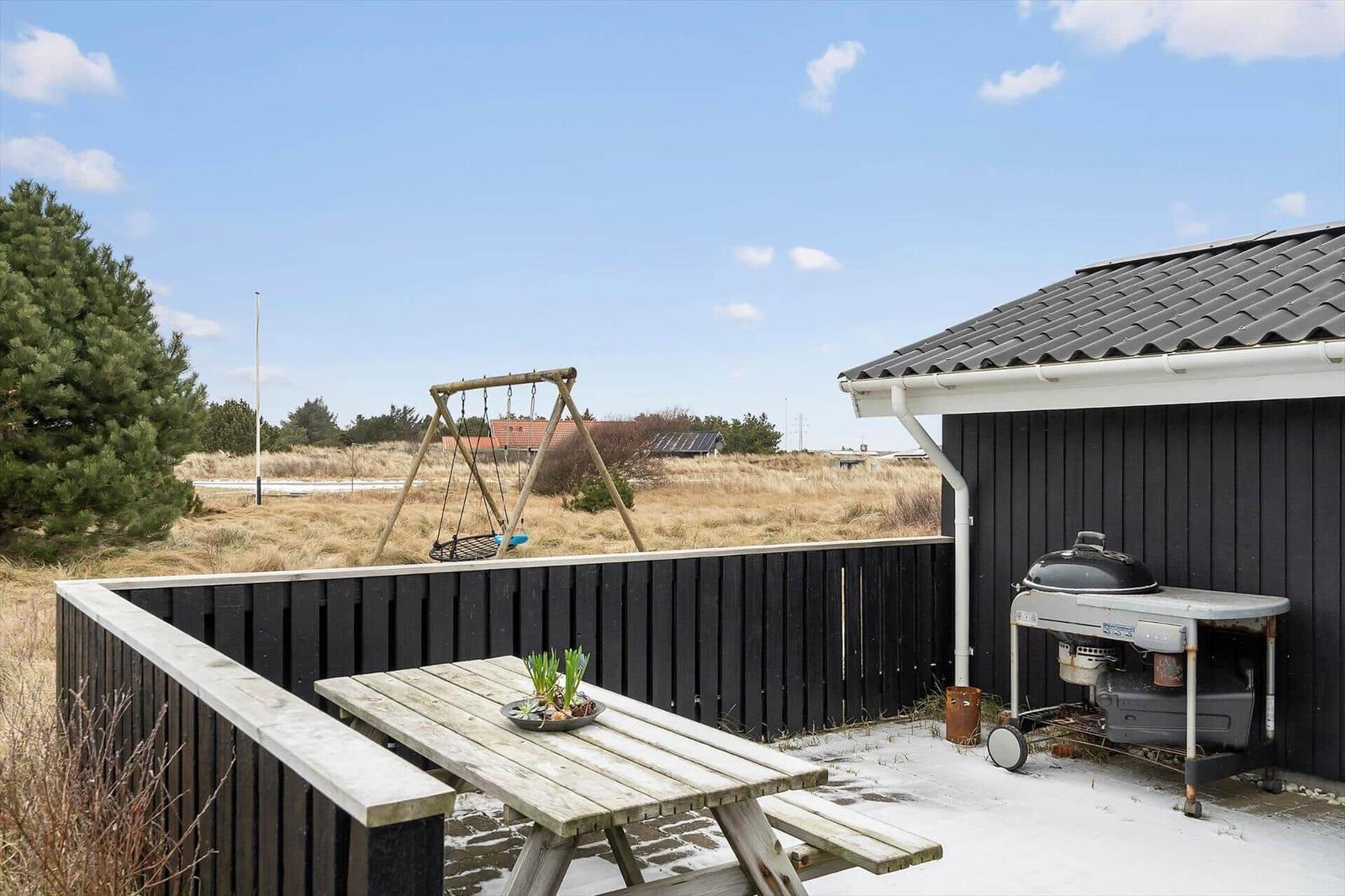 Terrasse mit Tisch, Grill und Schaukel im Freien.