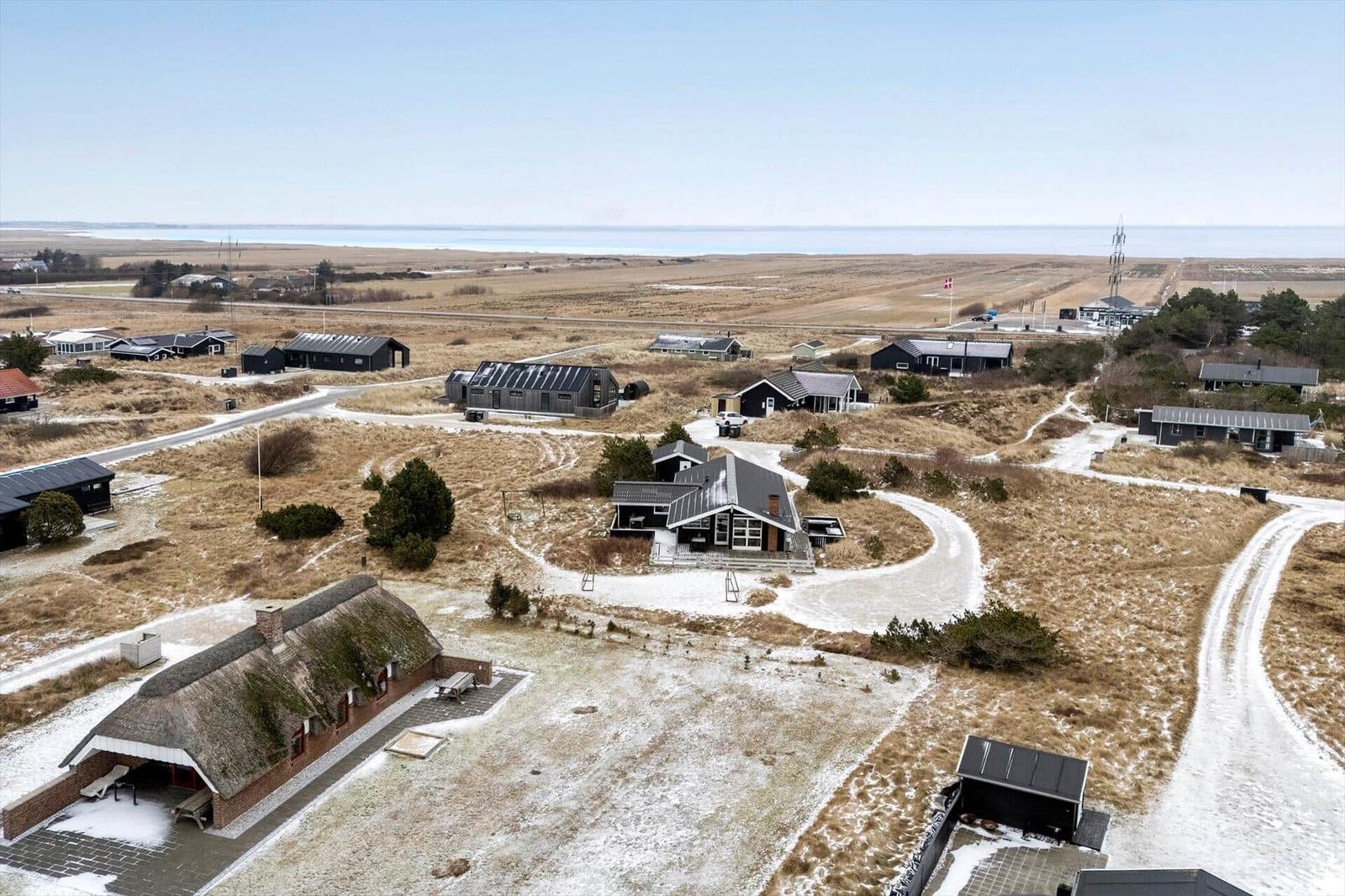 Übersicht über mehrere Häuser auf einer trockenen, schneebedeckten Landschaft mit Blick auf das Meer.