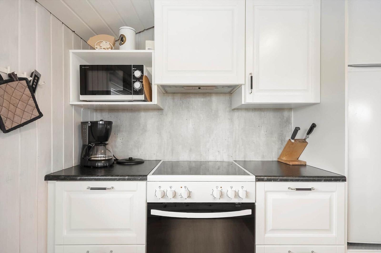 Küche mit weißen Schränken, schwarzer Arbeitsplatte und integriertem Herd.