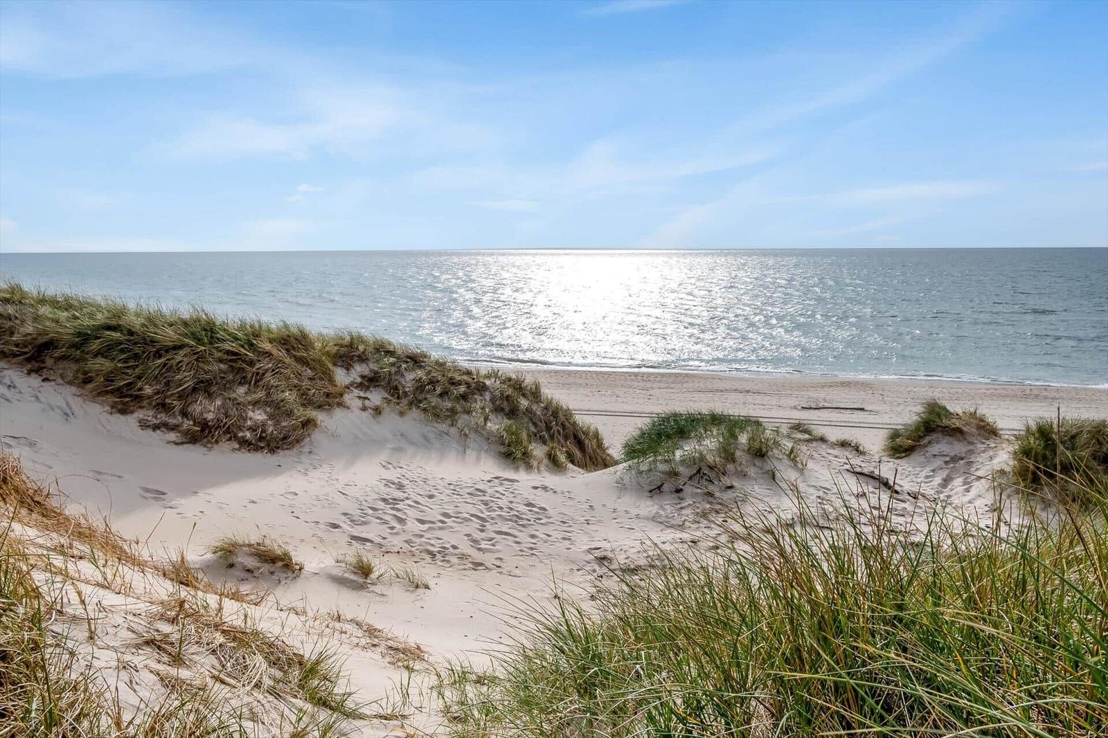 Strand mit Dünen und Meer unter blauem Himmel