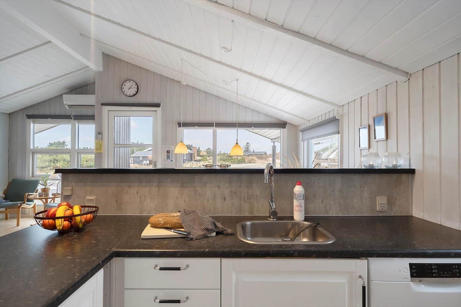 Küche mit Arbeitsplatte, Spüle und Fenstern zum Blick ins Freie.