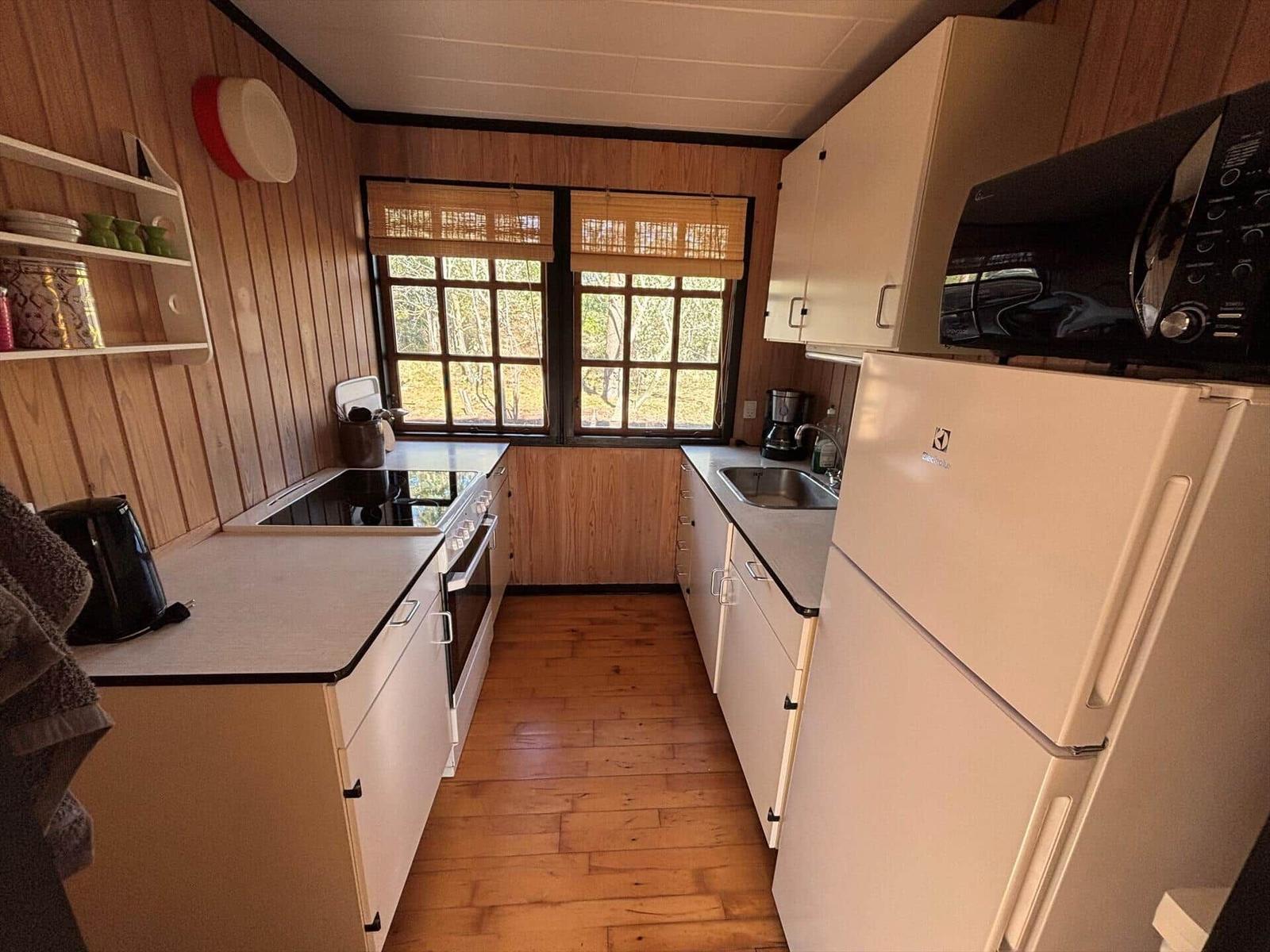 Kitchen with wood walls, fridge, stove, and windows