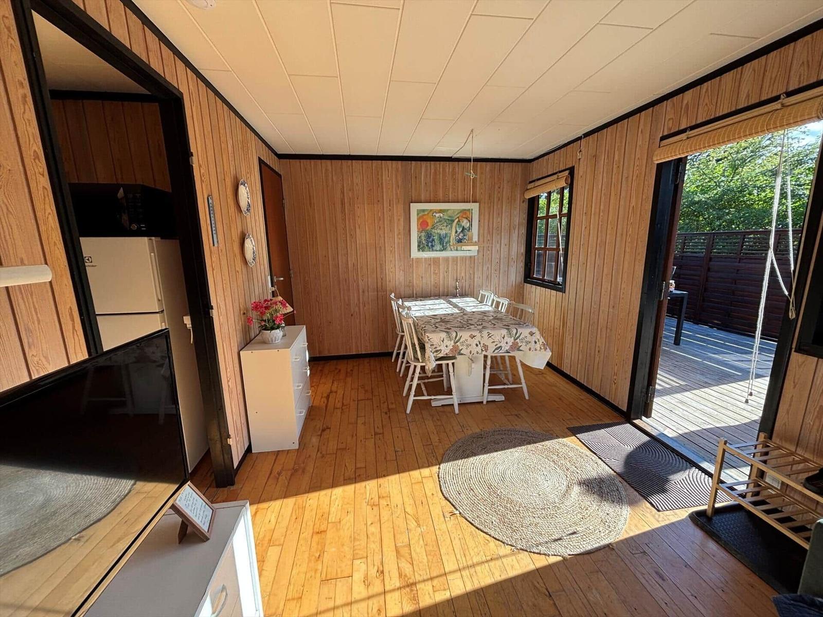 Dining room with table, chairs, and wood paneling. Access to kitchen and terrace.