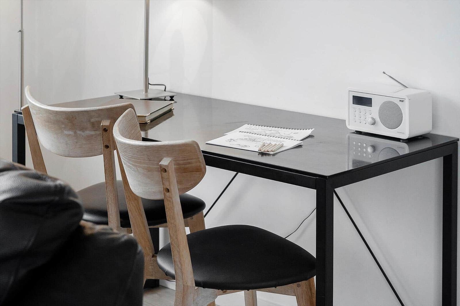 Schreibtisch mit zwei Stühlen, Lampe und Radio.