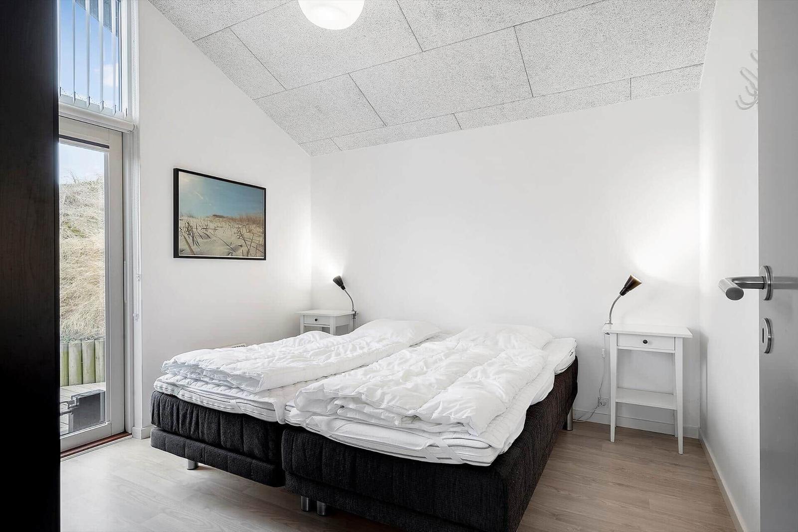 Schlafzimmer mit Doppelbett, zwei Nachttischen und Blick auf die Dünene Landschaft.