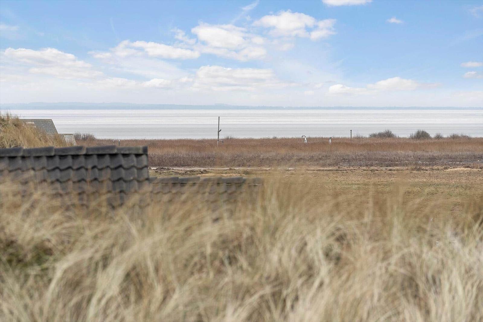Weitläufiger Blick auf See mit trockenem Gras und Steinmauer im Vordergrund.