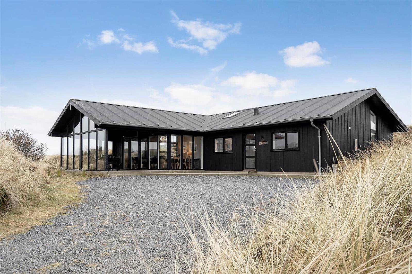 Moderne schwarze Hütte mit großem Glasbereich und Steinweg im Freien.