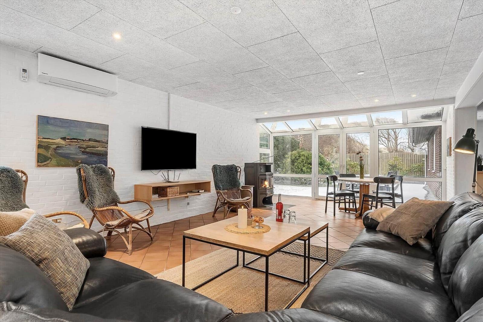 Wohnzimmer mit Sofa, Fernseher und Essbereich mit Blick auf Garten