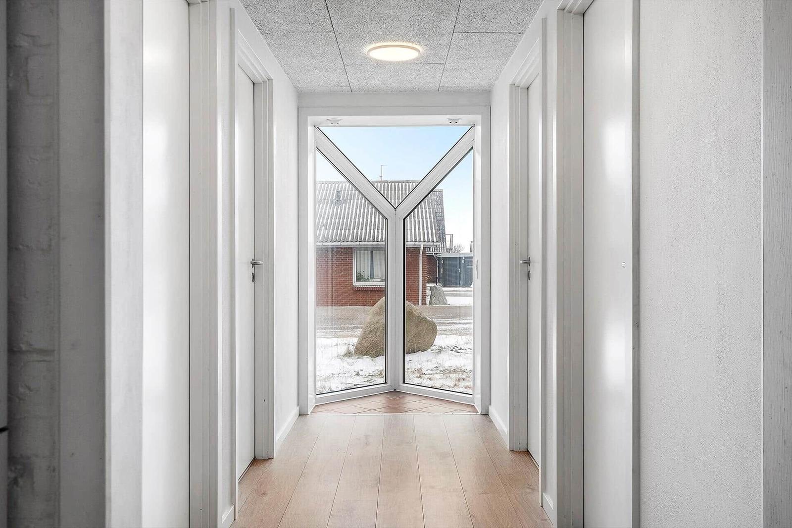 Hausgang mit Holzboden und Glasfront zur Außenterrasse