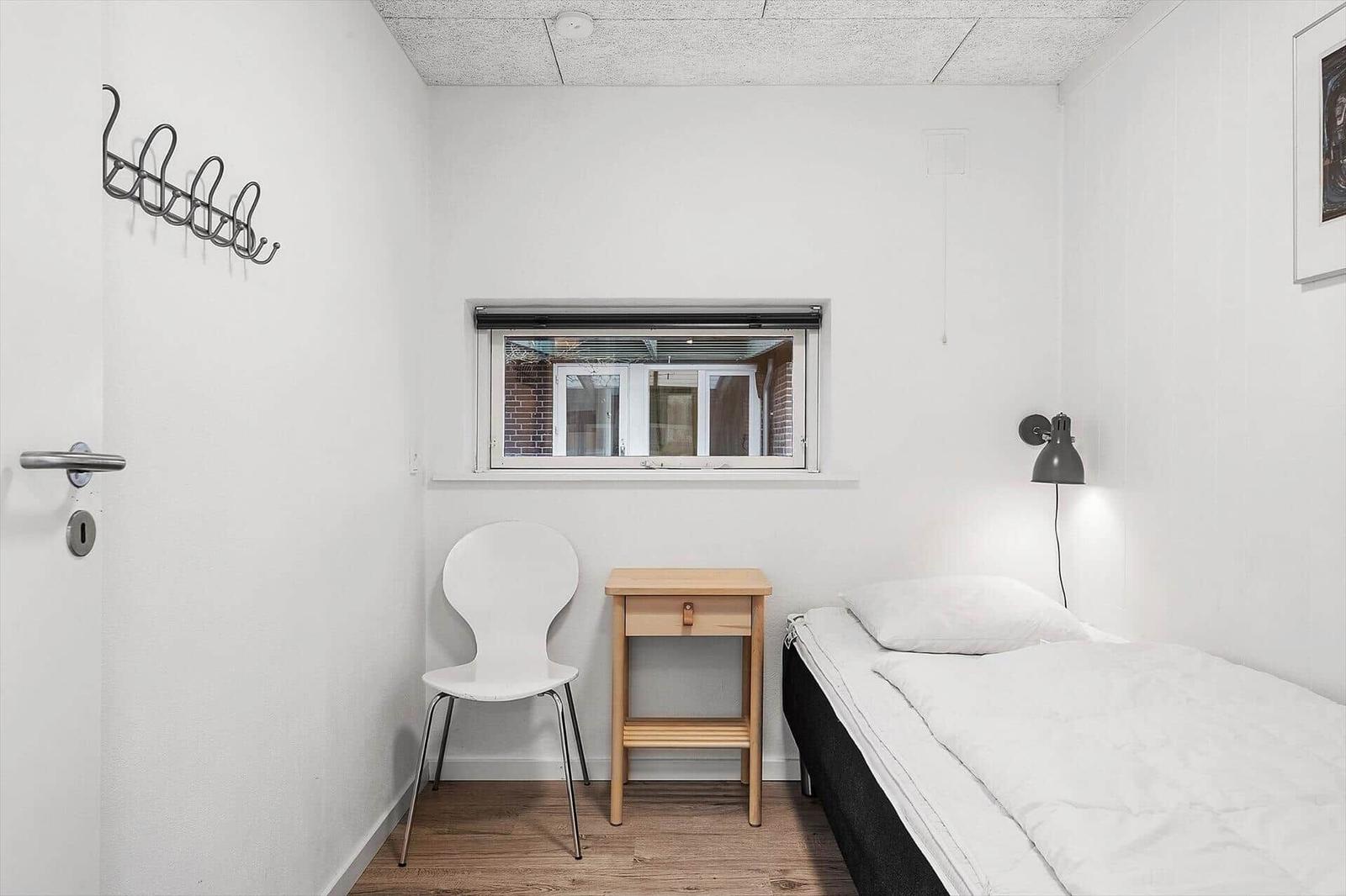 Ein Schlafzimmer mit Bett, Stuhl, Tisch und Fenster.