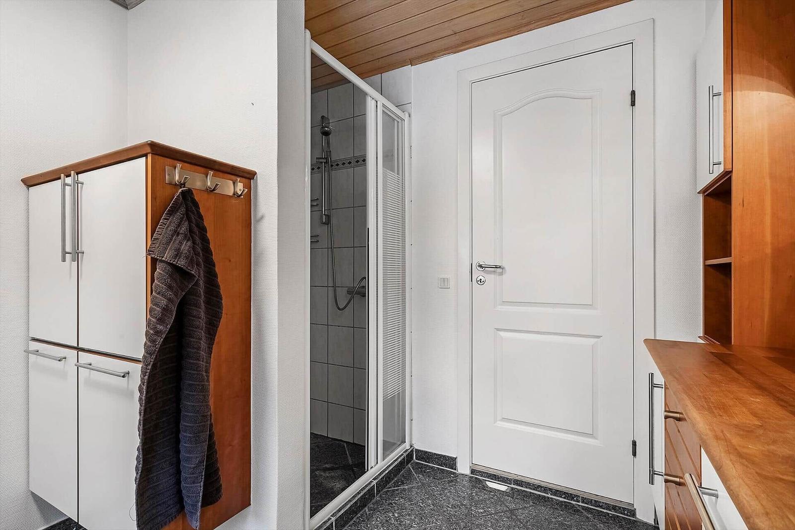 Dusche mit Glaswand, weiße Tür und Holzregale