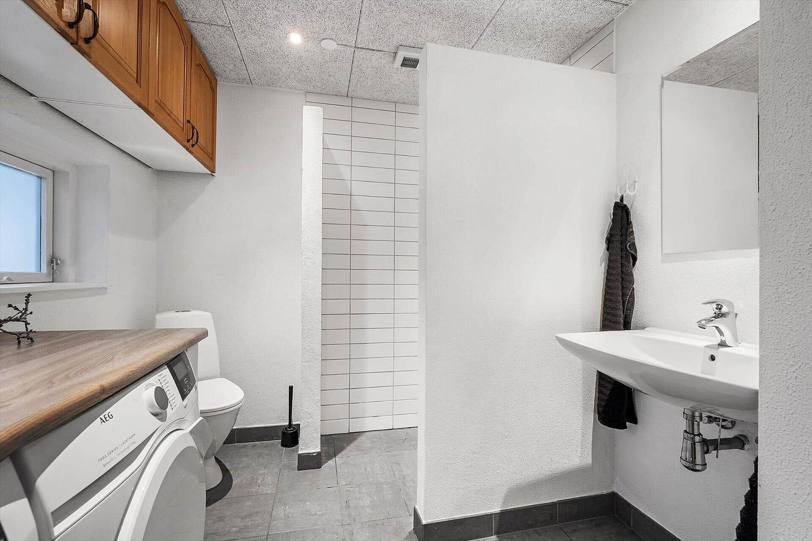 Badezimmer mit Waschmaschine, Toilette und Dusche.