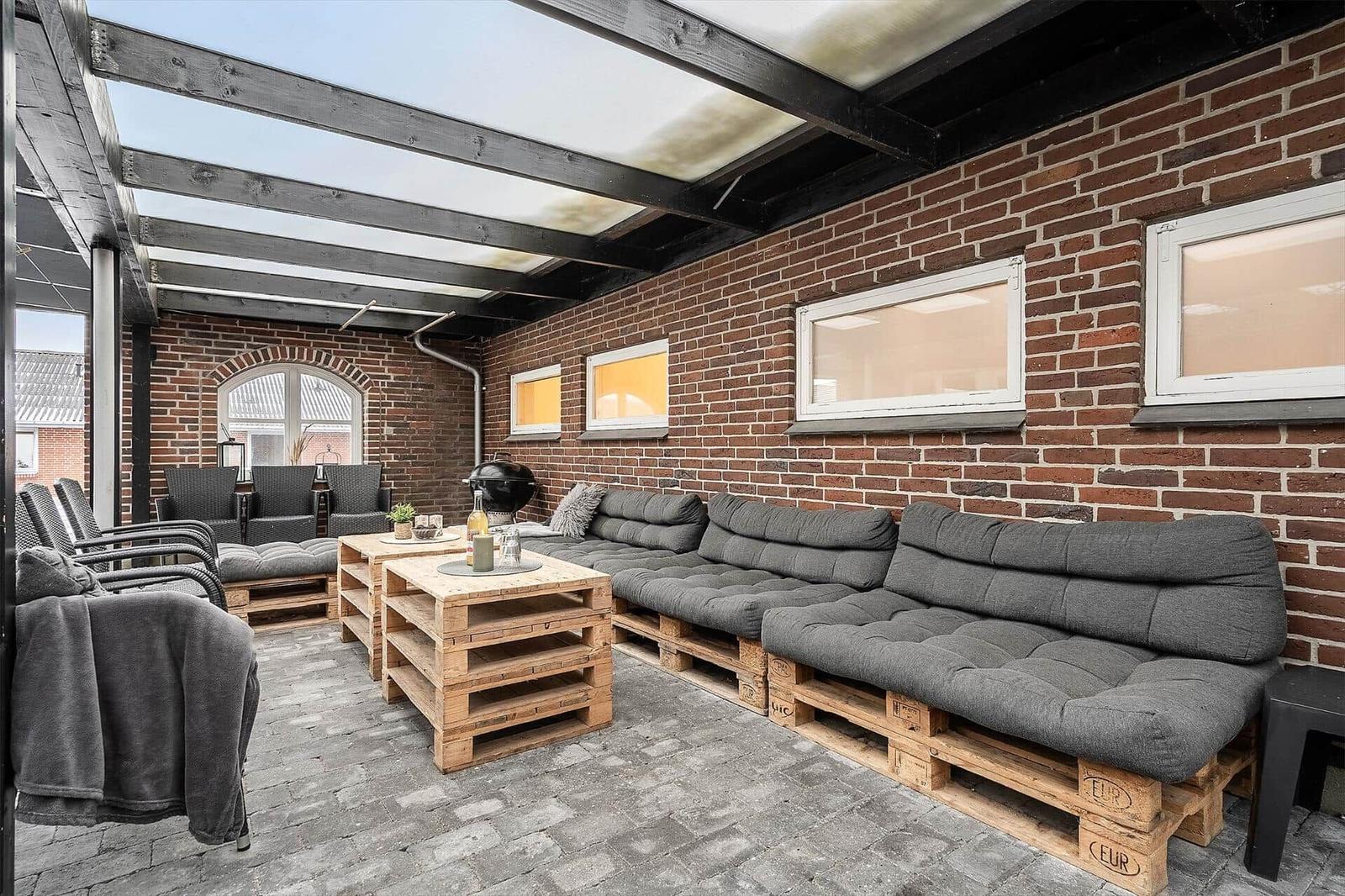 Terrasse mit Sitzgelegenheiten aus Paletten und Backsteinwand