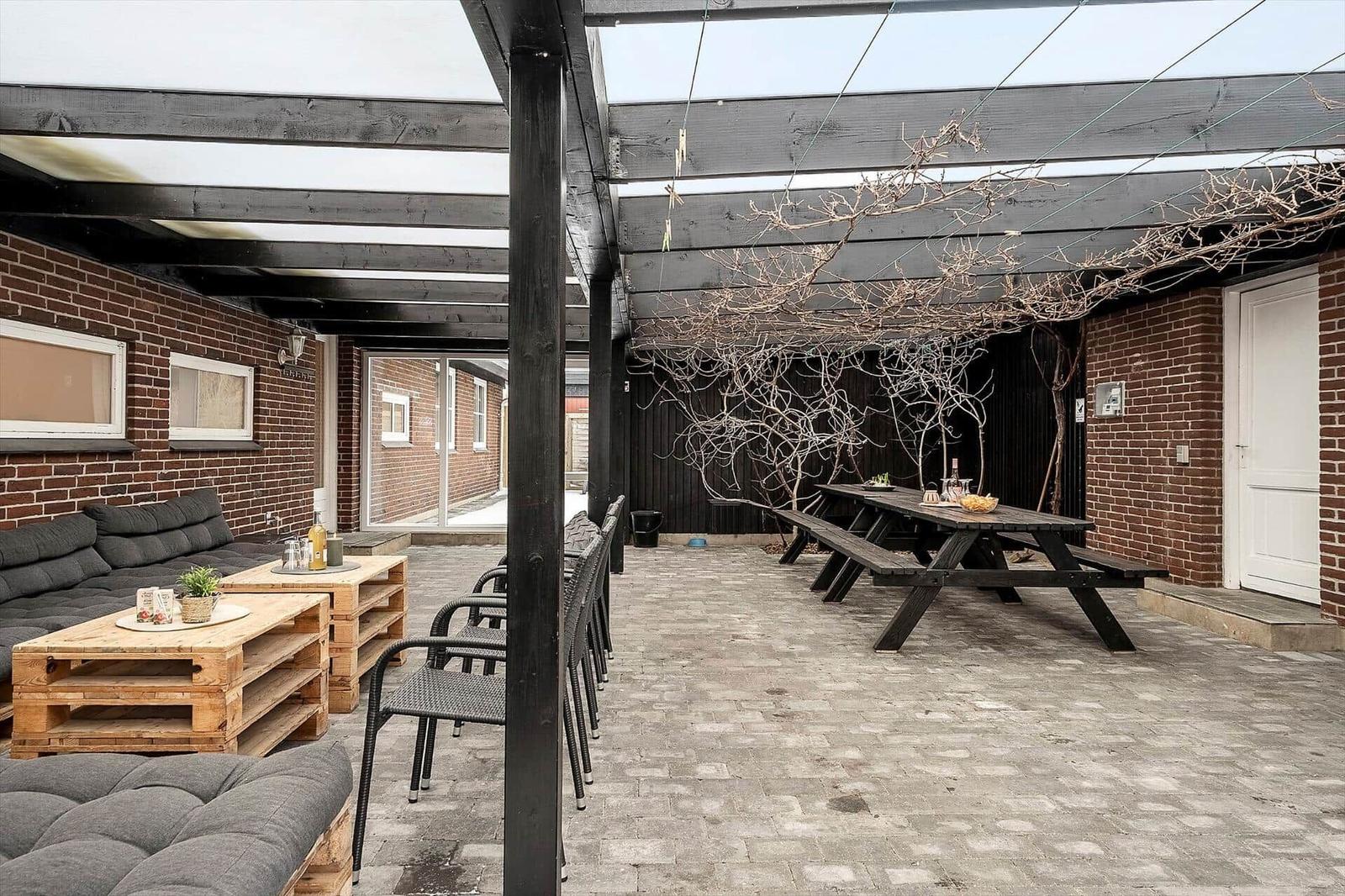 Terrasse mit Sitzgelegenheiten, Tisch und Pergola unter freiem Himmel.