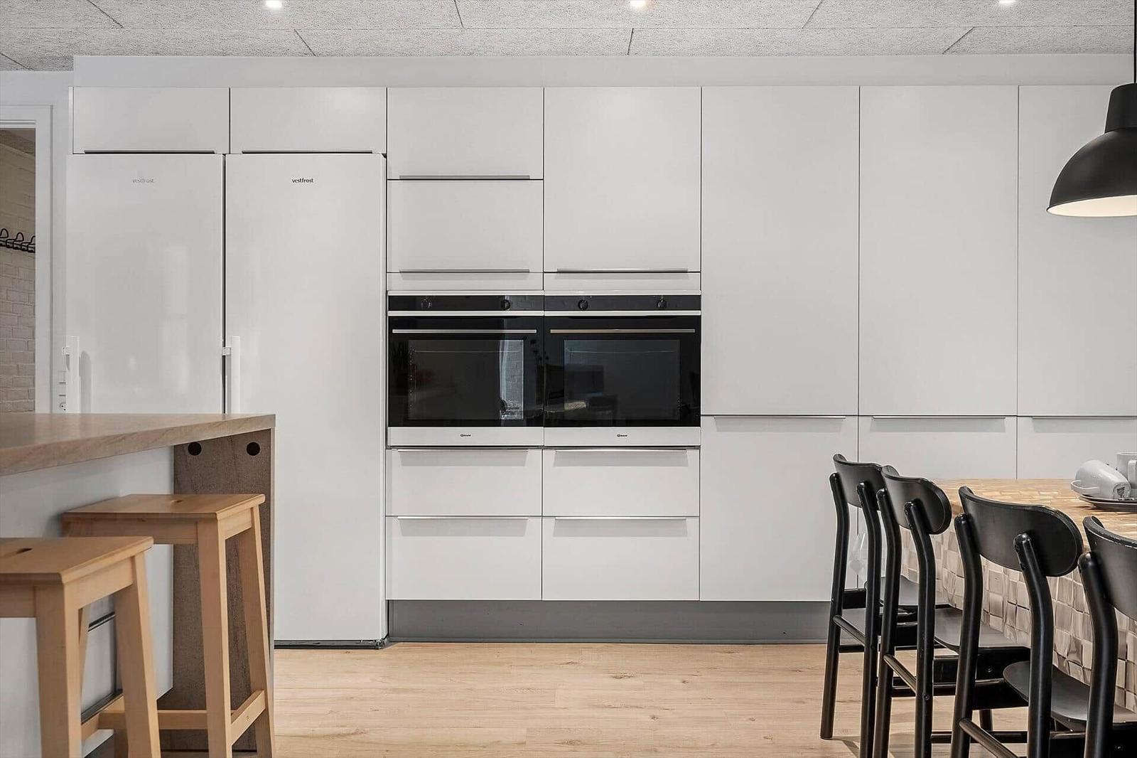 Moderne Küche mit weißen Schränken, integriertem Kühlschrank und Backofen.