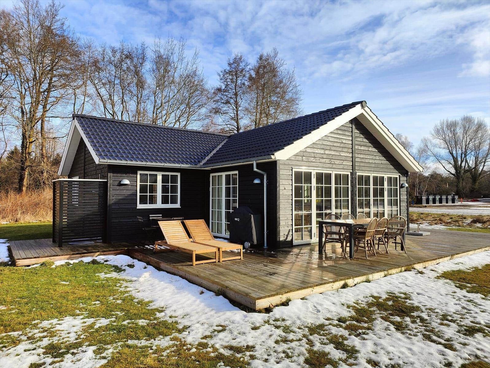 Wooden house with terrace, garden, and barbecue area in winter.