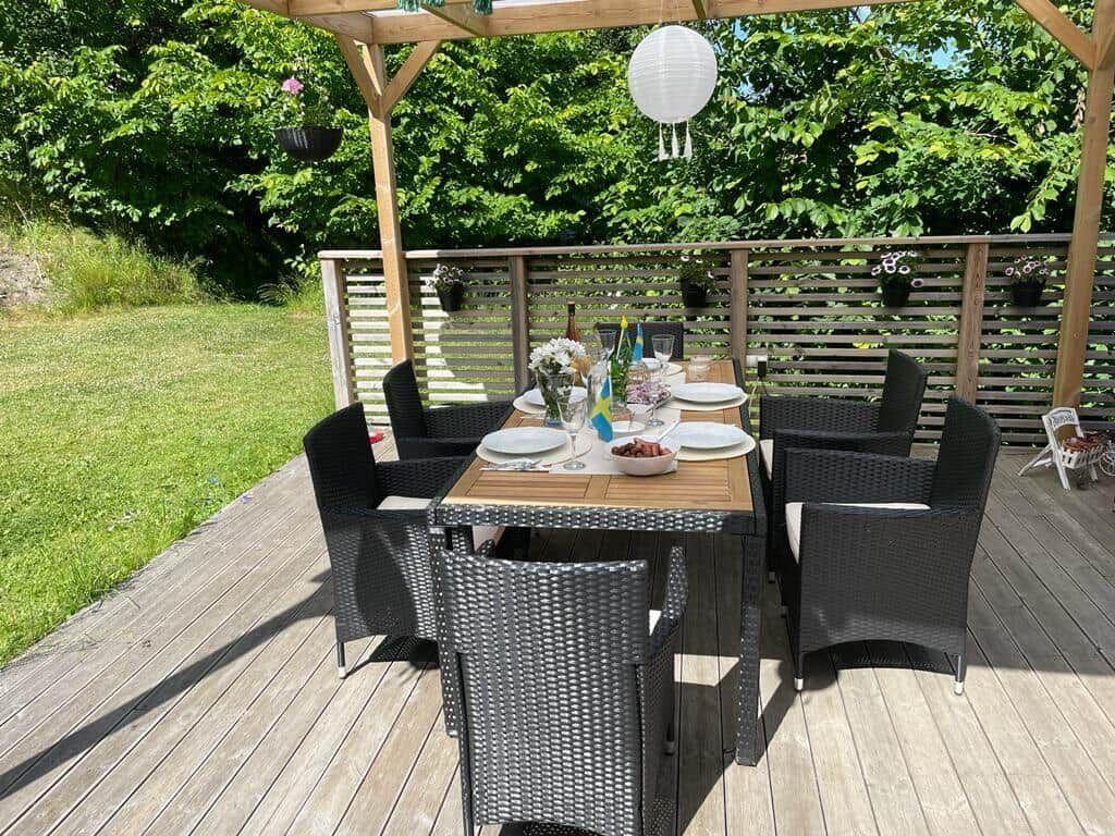 Holzterrasse mit Gedecktem Tisch und Stühlen unter Pavillon.