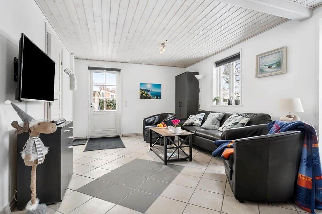 Living room with black leather furniture, TV, and window with view.
