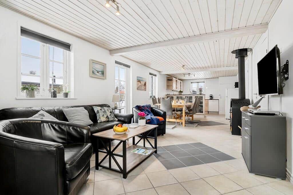 Living and dining area with sofa, coffee table, and kitchen in background.