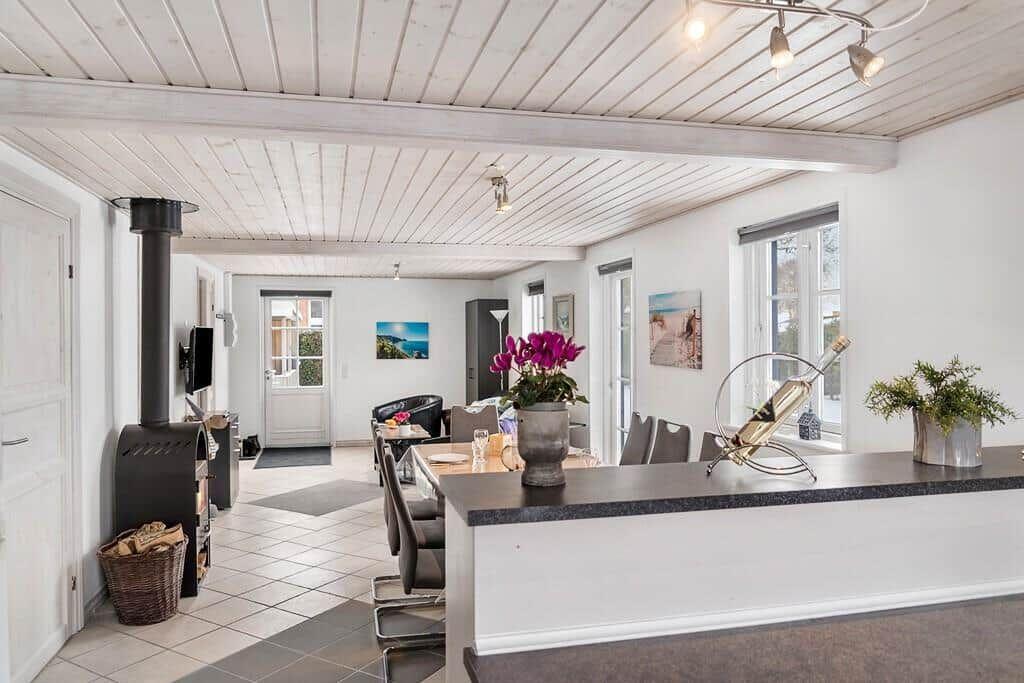 Entrance area with dining space, fireplace, and windows. Table with chairs and flowers.