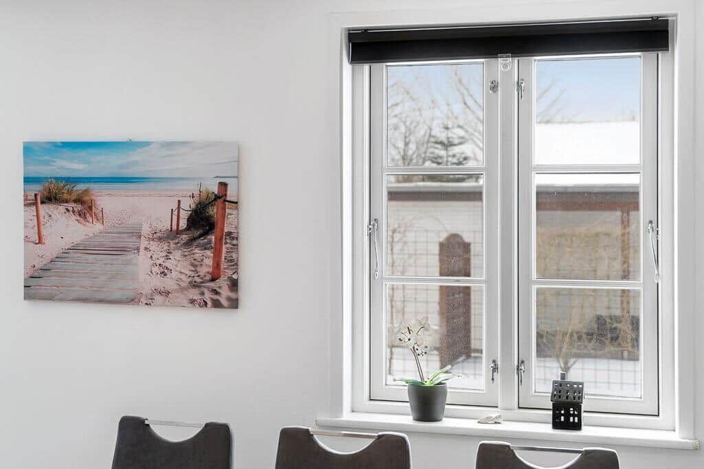 Window with view to outside, wall picture with beach motif and plants on windowsill.