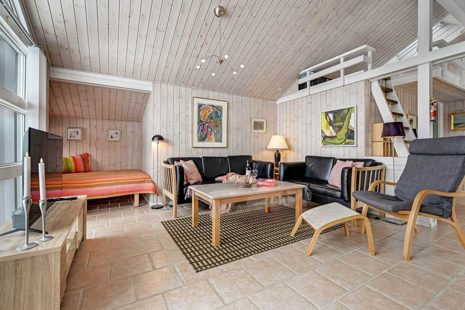 Wohnzimmer mit Sofa, Sessel und Betten unter Dachschräge