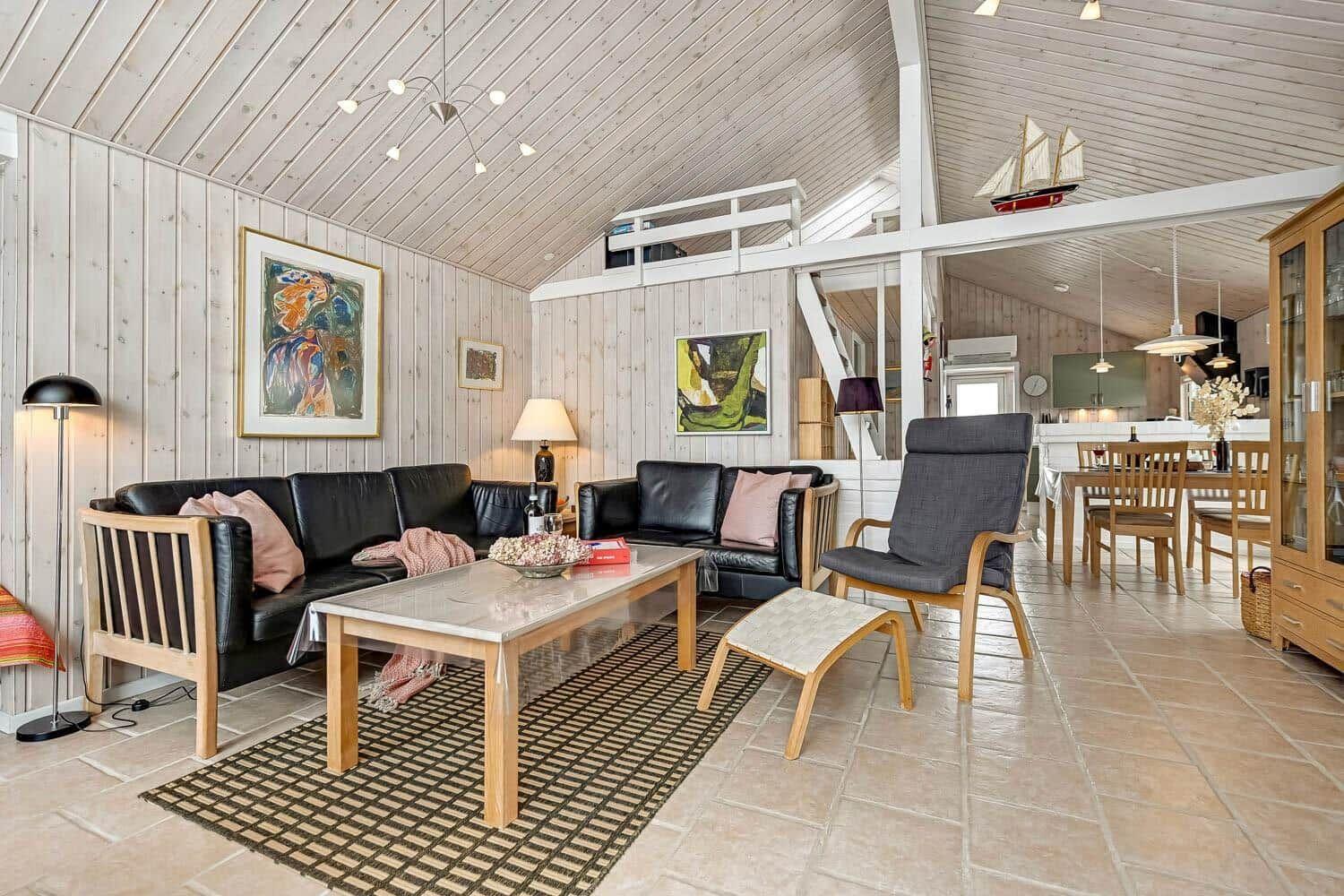 Wohn- und Essbereich mit Holzwänden, Sofa, Stuhl und Tisch.