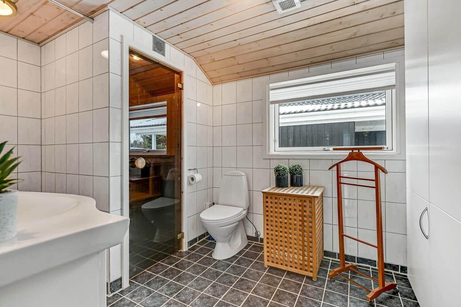 Badezimmer mit Toilette, Waschbecken und Blick in die Sauna.