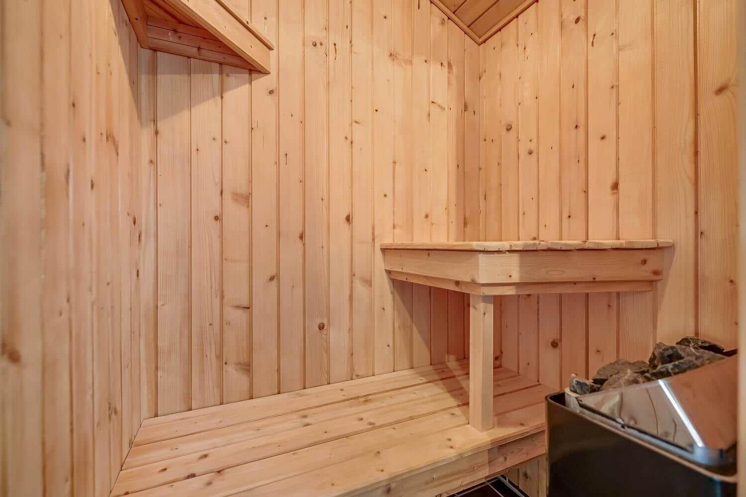 Holzsauna mit Sitzbänken und Steinkiste.